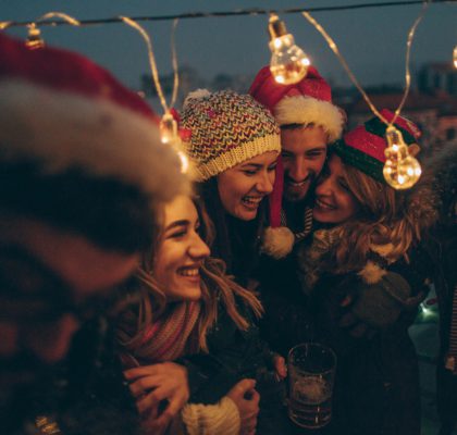 Photo of a group of friends celebrating New Year's and Christmas holidays by throwing a party on the balcony over the city, toasting to their friendship