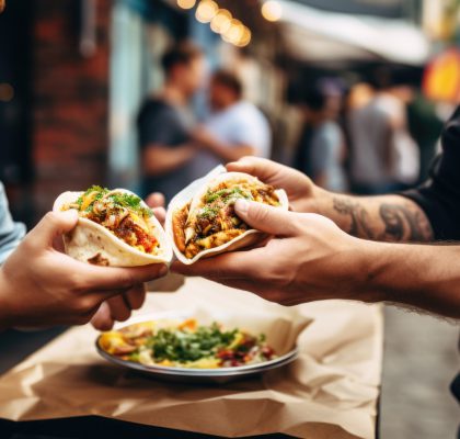 A chef gives a taco to a man at a street food market